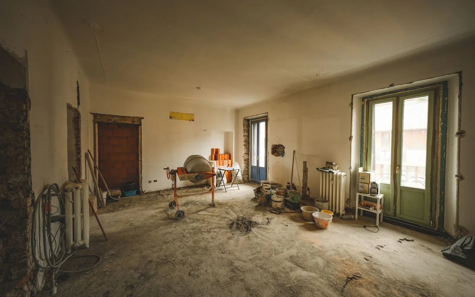 Stue under delvis renovering med malingsspann, verktøy og åpne overflater før rommet ferdigstilles